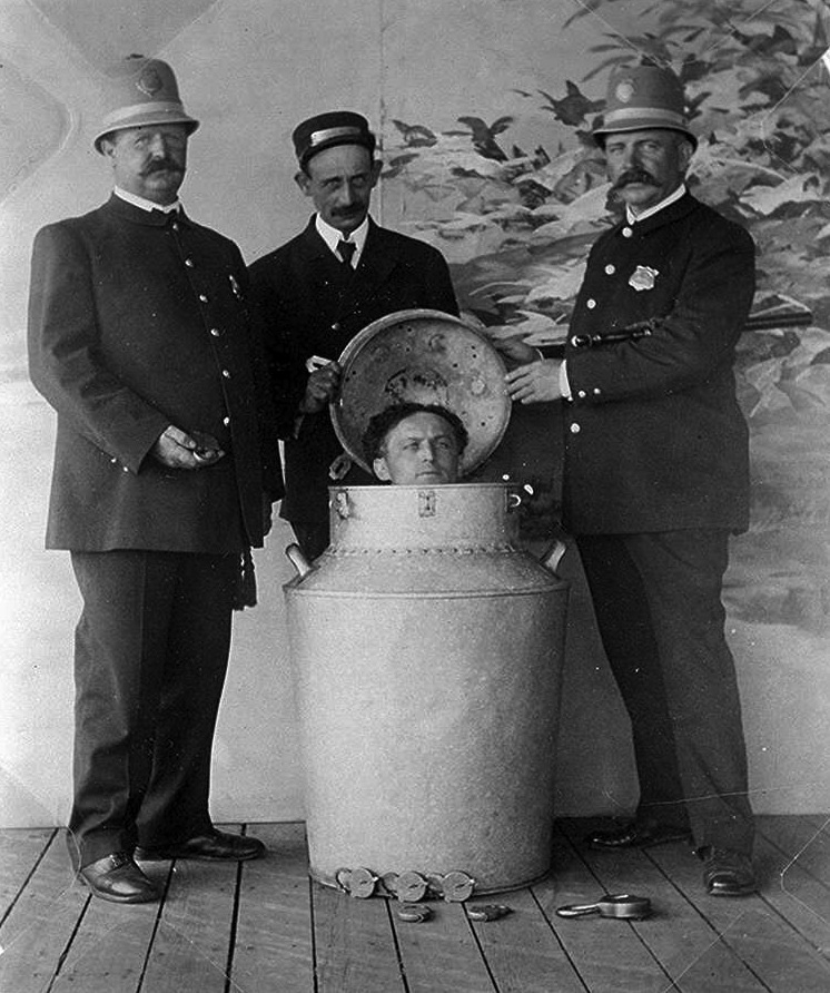 Houdini in his milk churn, surrounded by policemen