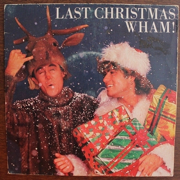 Two people are dressed festively, with one in a Santa suit and the other in a reindeer costume, surrounded by falling snow, holding presents, and standing under the text "Last Christmas Wham!".