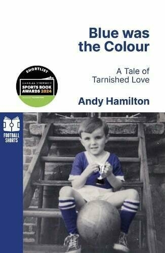 Auto-generated description: A young boy wearing a blue sports outfit sits on stairs, holding a trophy, featured on the cover of Blue was the Colour: A Tale of Tarnished Love by Andy Hamilton.